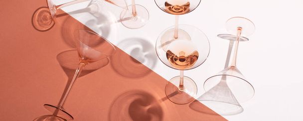 Розовое вино в коктейльных розовых бокалах на белом и розовом фоне - Фото, изображение