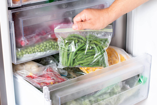 Tüten mit tiefgefrorenem Gemüse im Kühlschrank. Gefrorene grüne Bohnen, Nahaufnahme - Foto, Bild