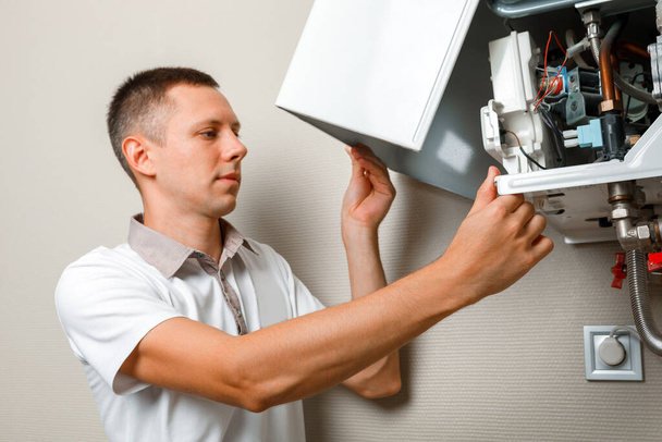 Plumber attaches Trying To Fix the Problem with the Residential Heating Equipment. Repair of a gas boiler - Foto, Imagen