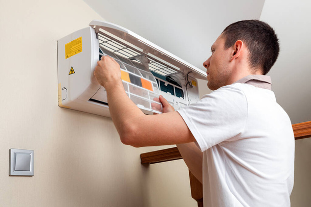 Male technician cleaning air conditioner indoors - Photo, image