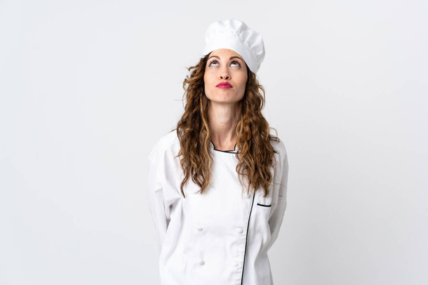 Young chef woman isolated on white background and looking up - Foto, Imagem