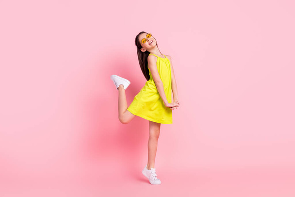 Full length photo of pretty charming schoolgirl dressed yellow outfit dark glasses dancing smiling isolated pink color background - Valokuva, kuva
