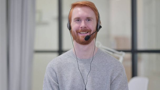 glimlachende baard roodharige man dragen headset met microfoon  - Foto, afbeelding