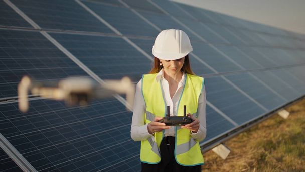 Portrait of a female engineer operating a drone on the background of a solar power plant. Photovoltaic solar panel installation. Solar array. New technologies. Investor and worker engineer - Photo, Image