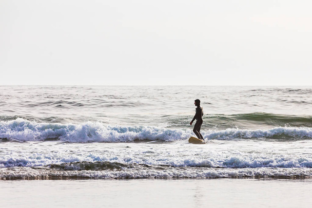 Ecola State Park, Όρεγκον, ΗΠΑ. 5 Μαΐου 2021. Άνθρωπος surfing κατά μήκος της ακτής Όρεγκον. - Φωτογραφία, εικόνα