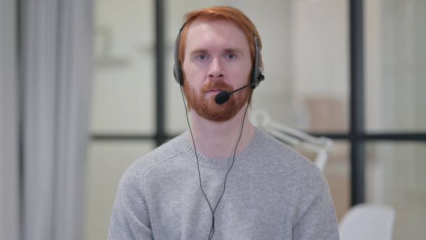 Junger Mann mit rotem Bart trägt Headset mit Mikrofon  - Foto, Bild
