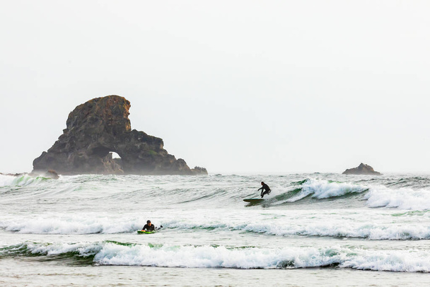Ecola State Park, Oregon, USA. May 5, 2021. Men surfing along the Oregon coast. - Zdjęcie, obraz