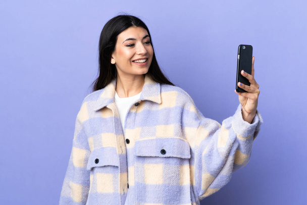 Giovane donna bruna su sfondo viola isolato facendo un selfie - Foto, immagini