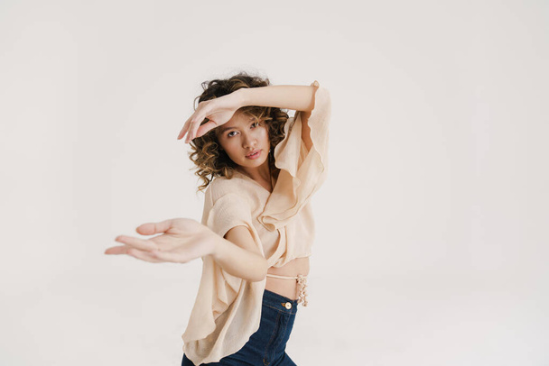 Young hispanic woman with curly hair dancing on camera isolated over white background - Foto, Bild