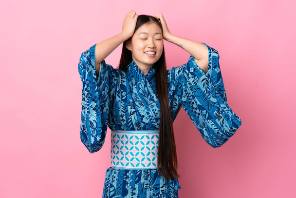 Young Chinese girl wearing kimono over isolated background laughing - Фото, зображення