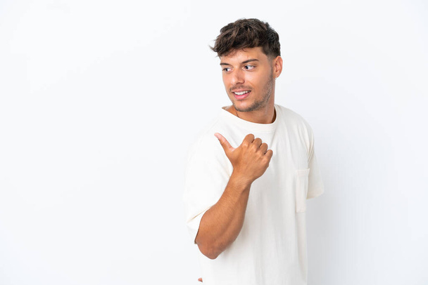 Junger kaukasischer gutaussehender Mann isoliert auf weißem Hintergrund, der zur Seite zeigt, um ein Produkt zu präsentieren - Foto, Bild