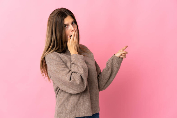Young slovak woman isolated on pink background with surprise expression while pointing side - Photo, Image