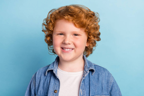Photo of positive glad nice small ginger boy toothy beaming smile wear denim jacket isolated blue color background - Фото, зображення
