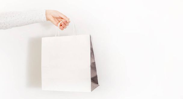 Una mano femenina sosteniendo una bolsa aislada sobre fondo blanco - Foto, imagen