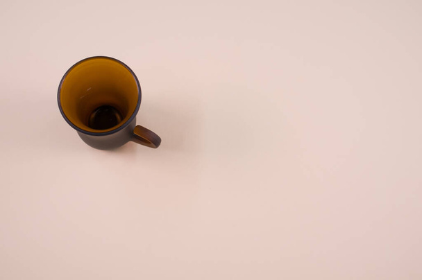 A closeup of a brown glass teacup on a beige-colored surface with text space - Fotoğraf, Görsel