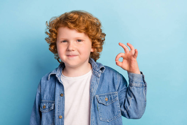 Photo of reliable positive promoter little boy show okey gesture wear jeans jacket isolated blue color background - Foto, immagini