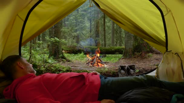 Bir turist çadırda yatar ve ormandaki yangına bakar. - Video, Çekim