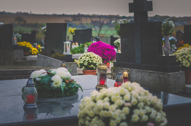 Свічки, квіти хризантеми, символи та інші прикраси на могилах на кладовищі під час Дня всіх святих.  - Фото, зображення