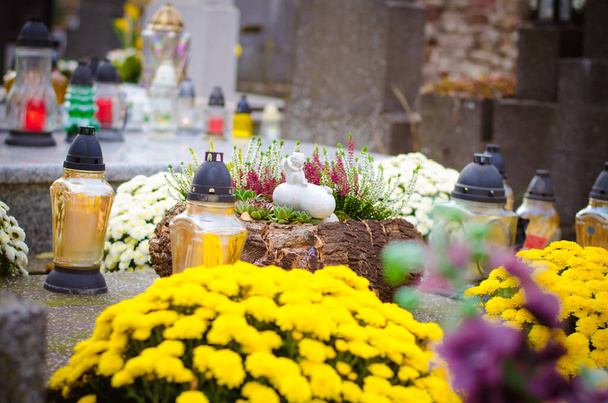 αναμμένα κεριά, κίτρινα χρυσάνθεμα λουλούδια και νεκρώσιμες θρησκευτικές διακοσμήσεις σε τάφους στο νεκροταφείο - Φωτογραφία, εικόνα