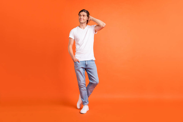 Full size photo of young happy dreamy positive man look empty space hand hair isolated on orange color background - Foto, imagen