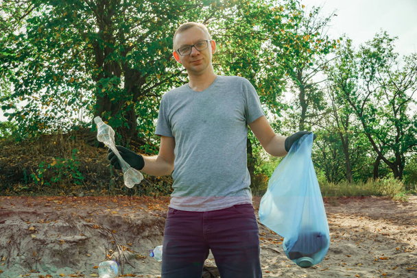 Volunteer man collects trash in the trash bag. Trash-free planet concept. Nature cleaning, volunteer ecology green concept. - Foto, Imagen