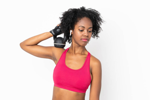 Giovane donna afroamericana isolata su sfondo bianco rendendo sollevamento pesi con kettlebell - Foto, immagini