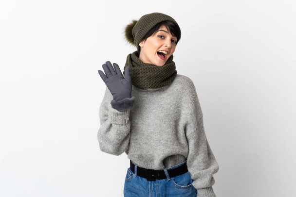 Fiatal lány téli kalap szalutál kézzel boldog arckifejezéssel - Fotó, kép