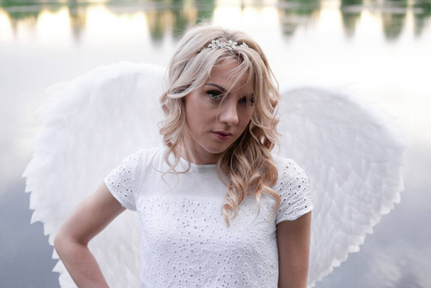 Portret blondynki w białej sukience i skrzydłach białych aniołów. Dobrzy ludzie. Niebo, Boże. rajski anioł - Zdjęcie, obraz
