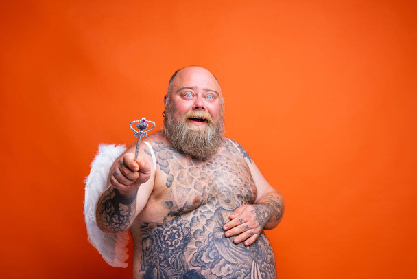 Жирный счастливый человек с бородой, татуировками и крыльями действует как волшебная фея - Фото, изображение