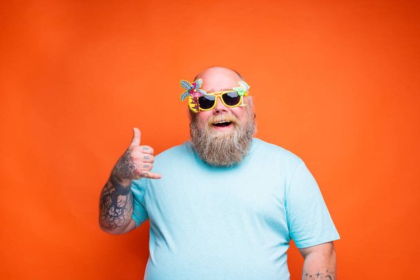 Gros homme heureux avec barbe, tatouages et lunettes de soleil est prêt pour l'été - Photo, image