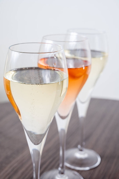 Proeverij van witte en brute rose champagne mousserende wijn uit fluitglazen - Foto, afbeelding