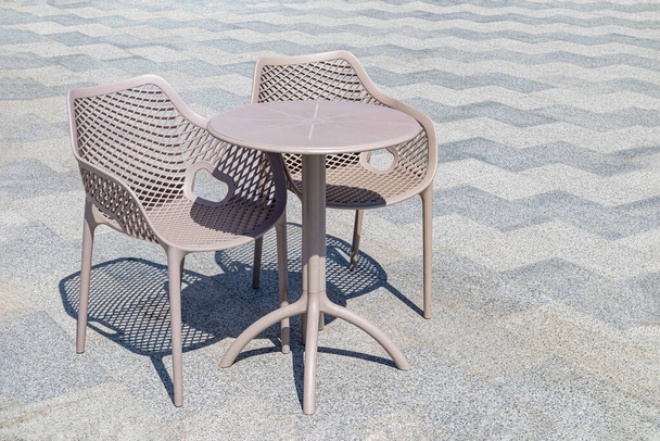 стол и стулья на кафельной плитке открытого кафе - Фото, изображение
