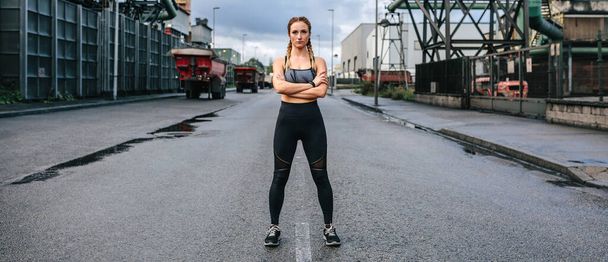 Sportlerin mit Kamera posiert vor Fabrik - Foto, Bild