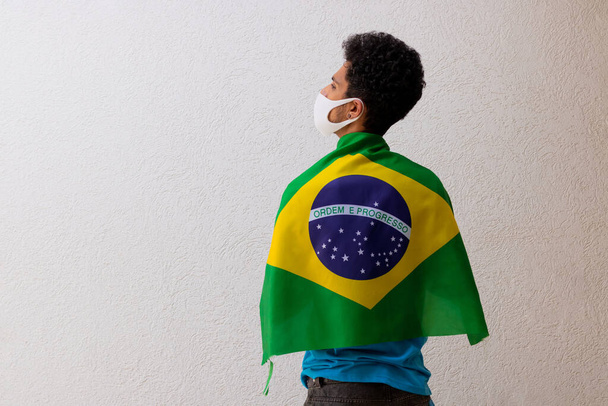 Zwarte man met pandemisch masker met Braziliaanse vlag geïsoleerd op wit - Foto, afbeelding