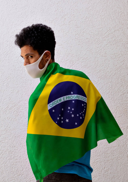 Black Man With Pandemic Mask Holding a Brazil Flag Isolated On White - Foto, Bild