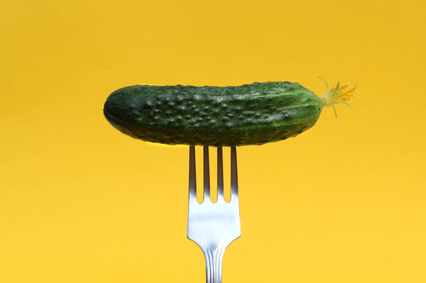 Fresh cucumber planted on a fork on a yellow background. - Zdjęcie, obraz