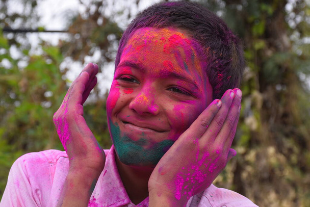 Мальчик играет с цветами, в хорошем настроении. Концепция фестиваля в Индии holi - Фото, изображение