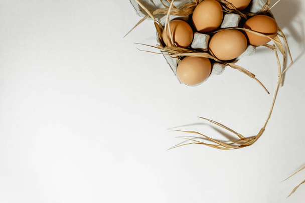Chicken eggs in a paper tray on a grass straw. top view. Copy space. - Photo, image