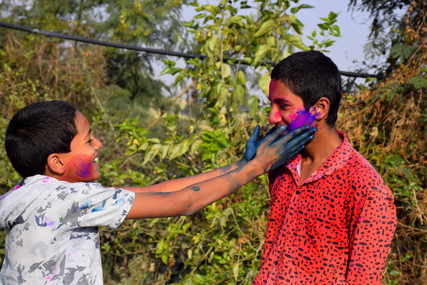 Δύο αγόρια παίζουν σε χρώματα σε χαρούμενη στάση, Concept for Indian festival Holi - Φωτογραφία, εικόνα