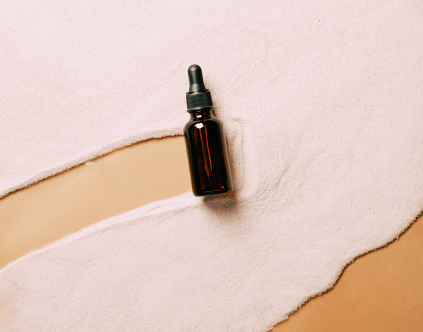 美容液オイル化粧品製品ビーチ砂の背景のボトル。概要砂浜を背景にした製品表彰式 - 写真・画像