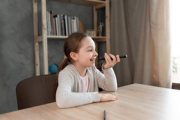 Voice assistant. Happy girl dictates text using microphone of smartphone or mobile phone. student on the phone records an audio message. Voice sms recording.copy space - Photo, Image