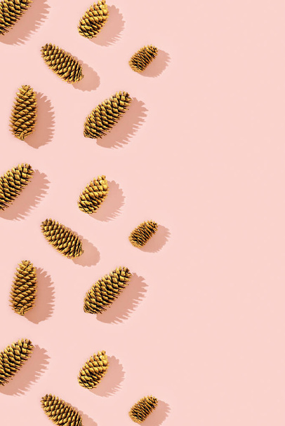 Christmas pattern from natural pine cone painted golden colored on pink. Trendy winter holiday background with copy space. - Zdjęcie, obraz