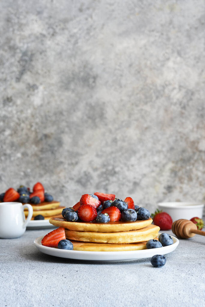 Homemade pancakes with strawberries and blueberries for breakfast on the kitchen table. - Foto, Imagen