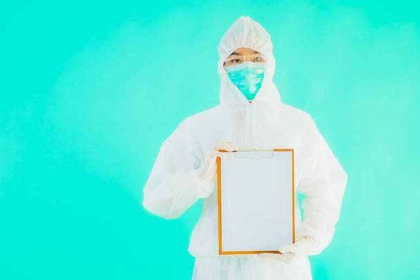 肖像画美しい若いアジアの医師の女性は、青の隔離された背景に空のカードホワイトボードでコロナウイルスやcovid19から保護するためのパイプや個人的な保護具を着用 - 写真・画像