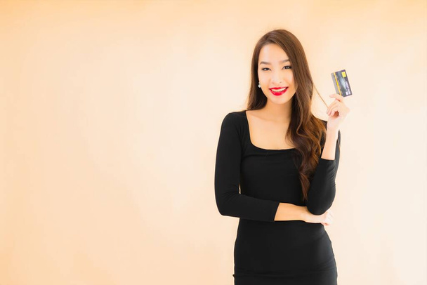 Портрет красива молода азіатка з кредитною карткою для покупок на кольоровому ізольованому фоні
 - Фото, зображення