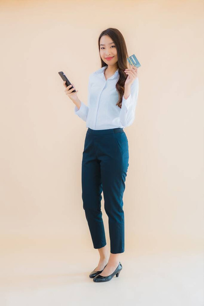 Retrato hermosa joven negocio asiático mujer con teléfono y tarjeta de crédito en color aislado fondo - Foto, imagen
