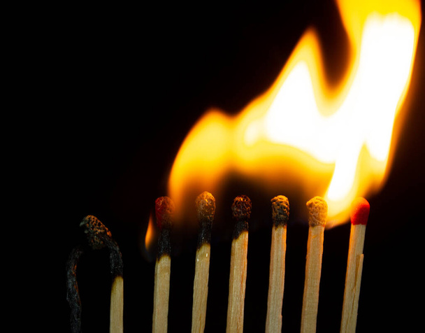 Gruppo di fiammiferi rossi bruciati isolati su sfondo nero. Riga che brucia nella reazione a catena - Foto, immagini