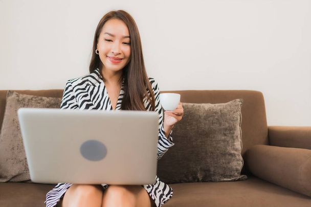 Портрет красивая молодая азиатская женщина использовать компьютер ноутбук на диване в гостиной внутренней области - Фото, изображение