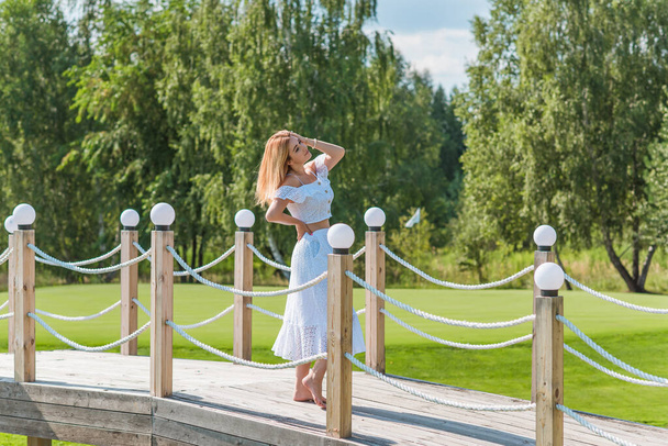 Lady in white cotton suit, crop top and skirt at nature, vacation scene - 写真・画像