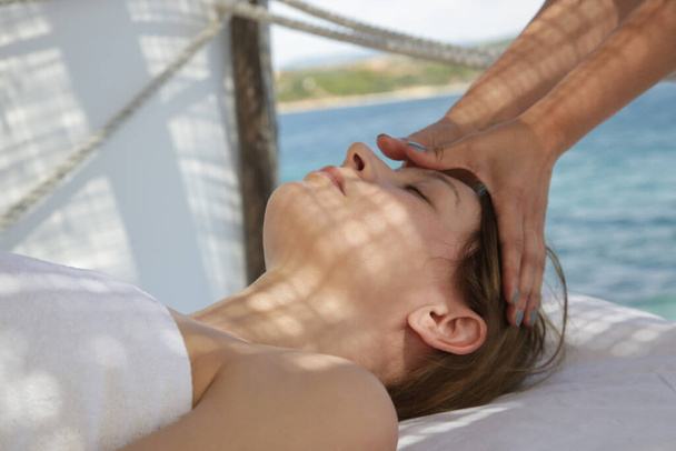 Mulher fazendo massagem facial em tenda de spa na praia. - Foto, Imagem